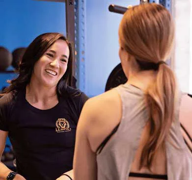 Smiling fitness coach talking with a female client during a one-on-one training session in at Legacy Personal Training.